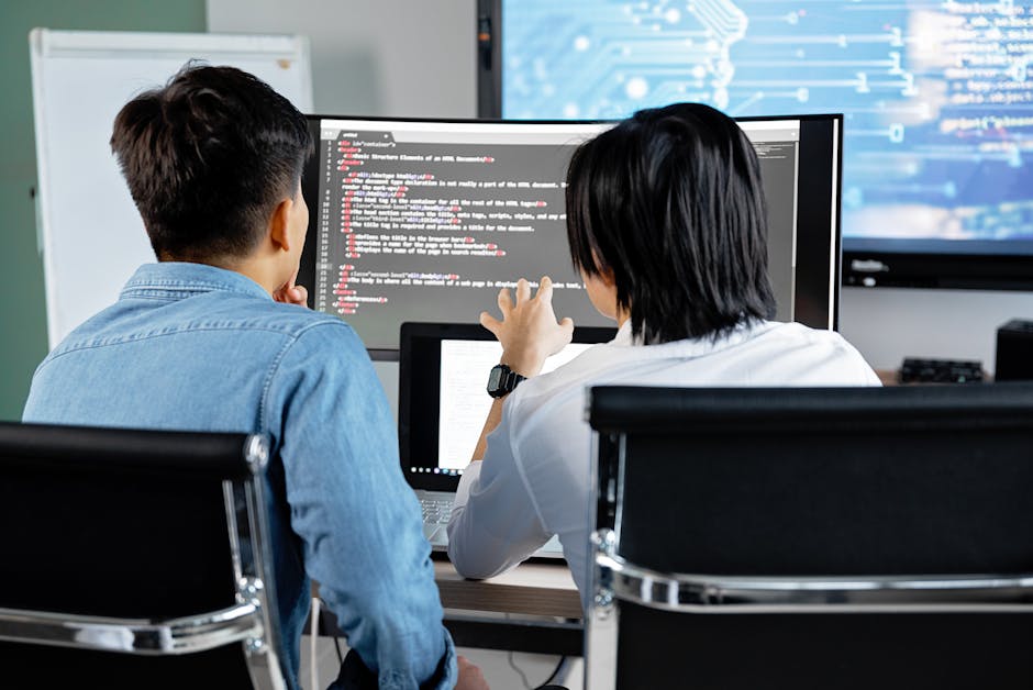 Two developers working together in an office, discussing code on a screen. Technology teamwork setting